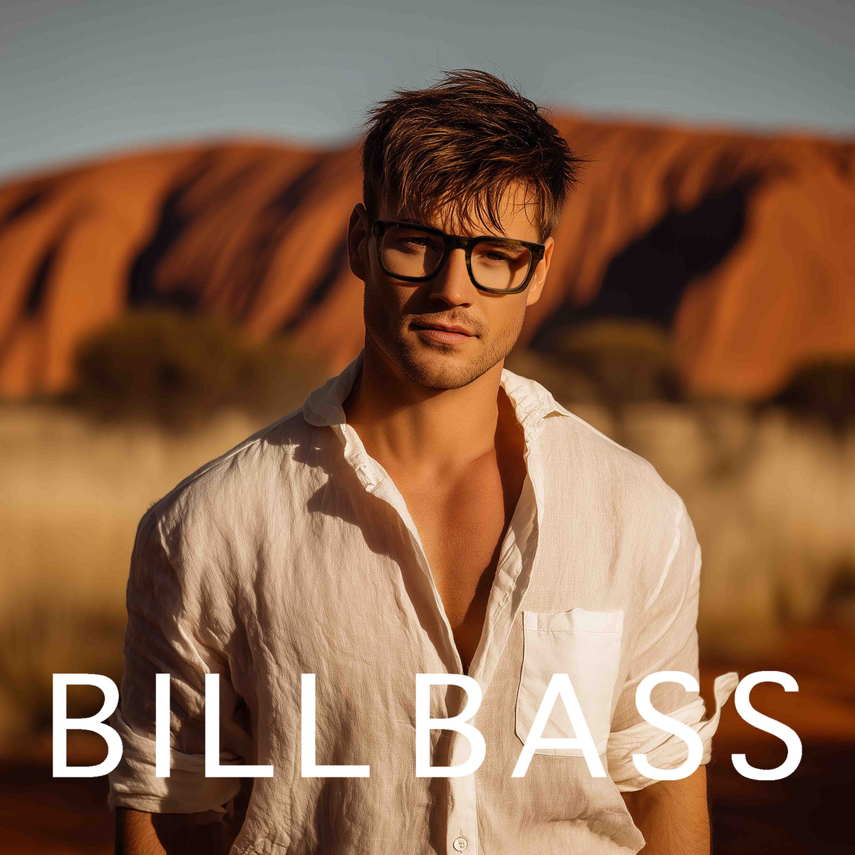 A man wearing black rectangular eyeglasses and an open white shirt stands outdoors in front of a warm-toned desert rock formation. Large white text at the bottom reads BILLBASS.